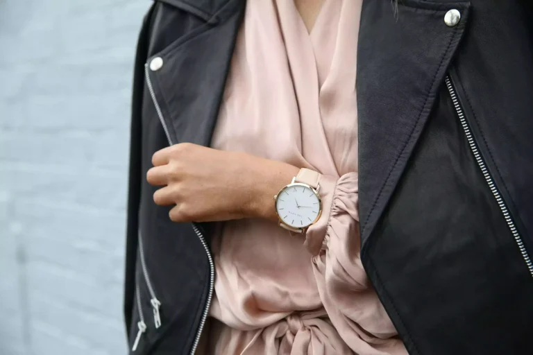 Femme portant un perfecto en cuir noir, une blouse rose pâle et une montre à son poignet
