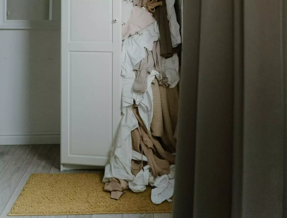 Comment ranger ses vêtements quand on a pas de place. Photo d'une armoire blanche débordant de vêtements