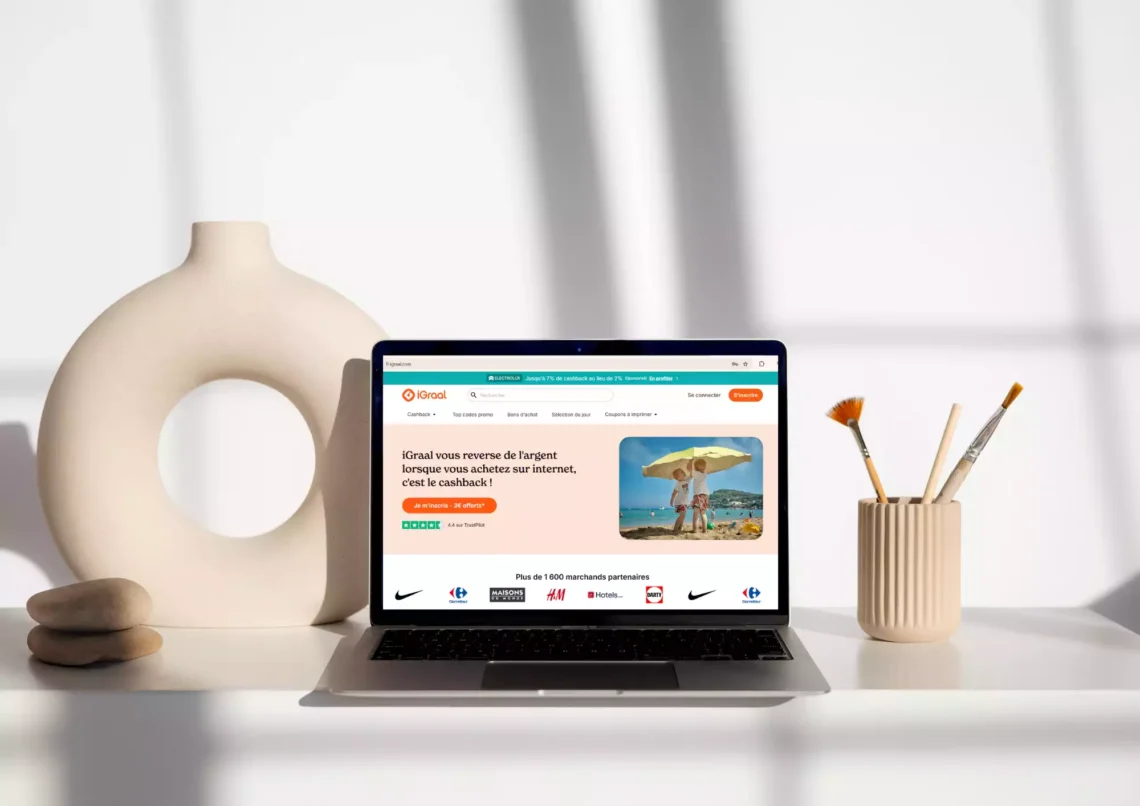 avis sur igraal cashback. Photo d'un bureau avec un ordinateur où l'on voit le site de cashback iGraal. Il y a aussi un vase et un pot à crayons dans des tons clairs.