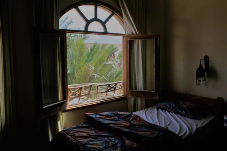 chambre avec une grande fenêtre en arche, ouverte, avec les rideaux qui volent
