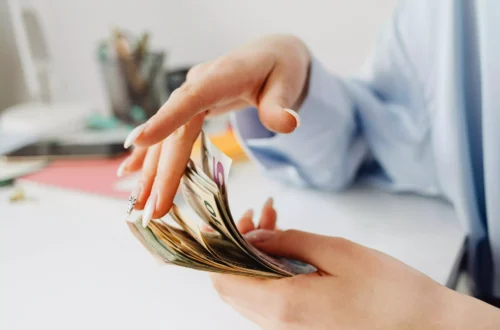mains de jeune femme en train de jouer avec une liasse de billets en euro