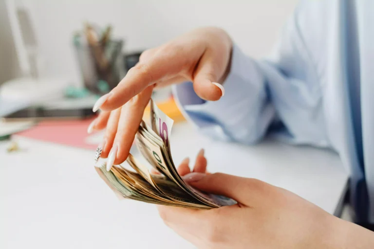 mains de jeune femme en train de jouer avec une liasse de billets en euro